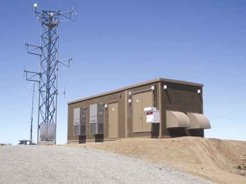 Telecommunications equipment shelter beside a communications tower