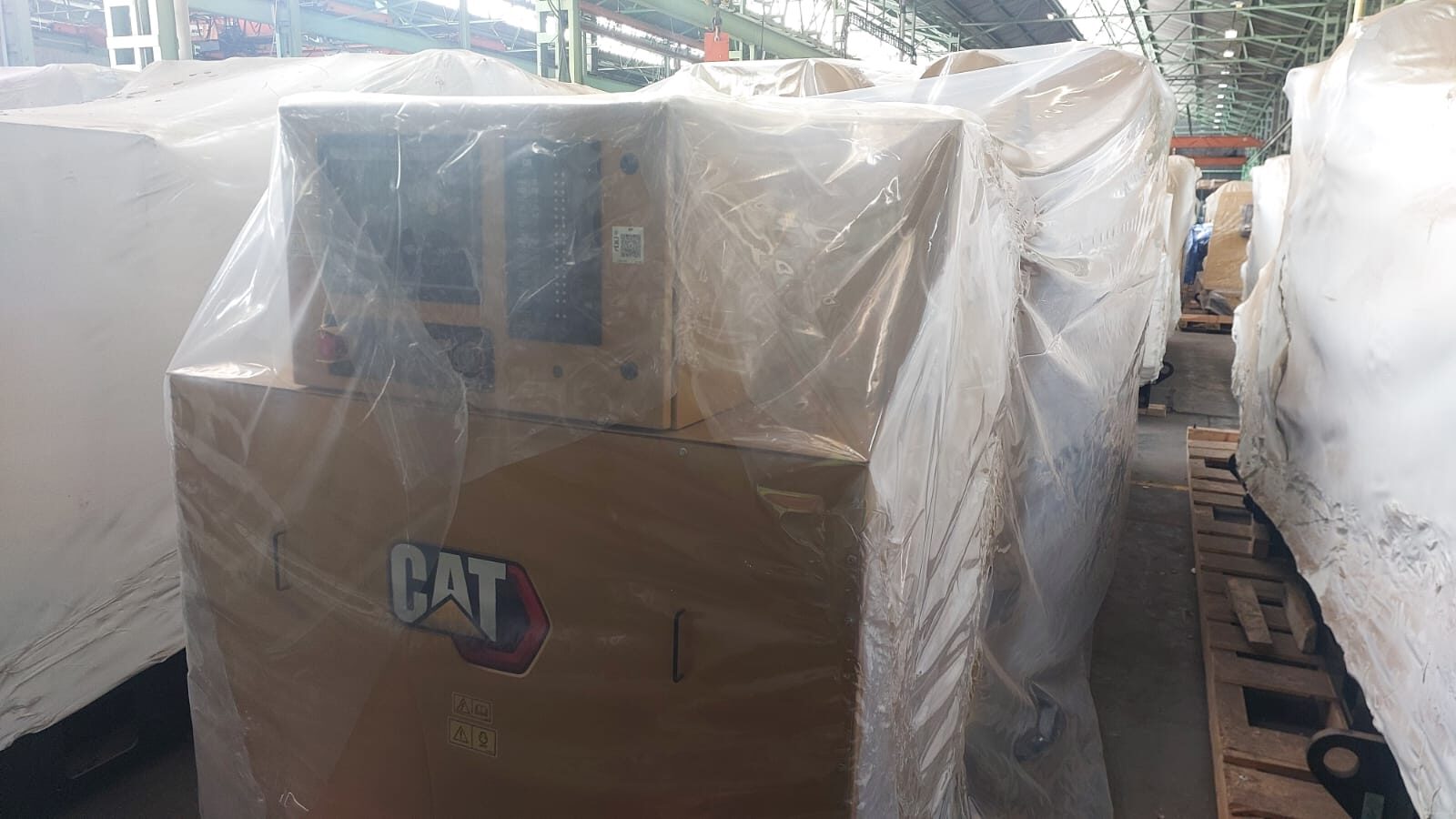 Factory-new Caterpillar 3516E generator set in protective wrap with CAT branding