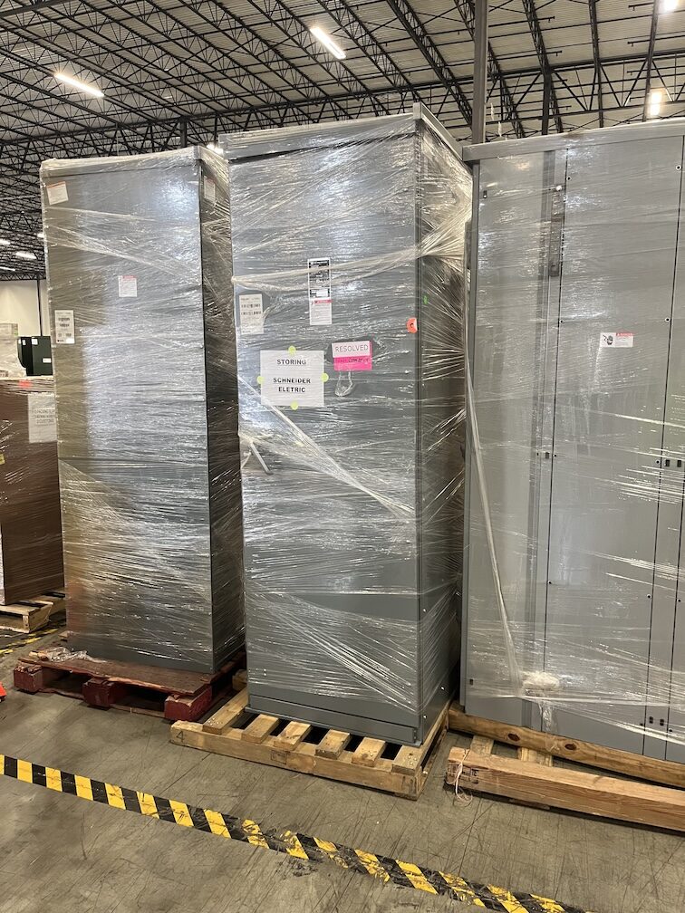 Rows of new surplus switchboards and MCC sections palletized in warehouse