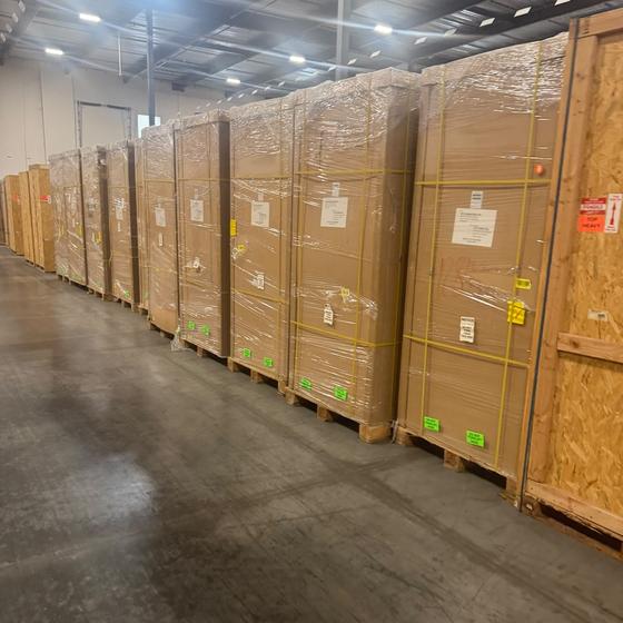 Rows of crated Volta and BTC Power EV charging stations in warehouse